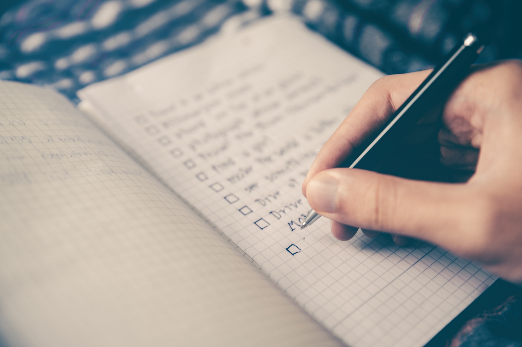 Person writing down itinerary in a notebook