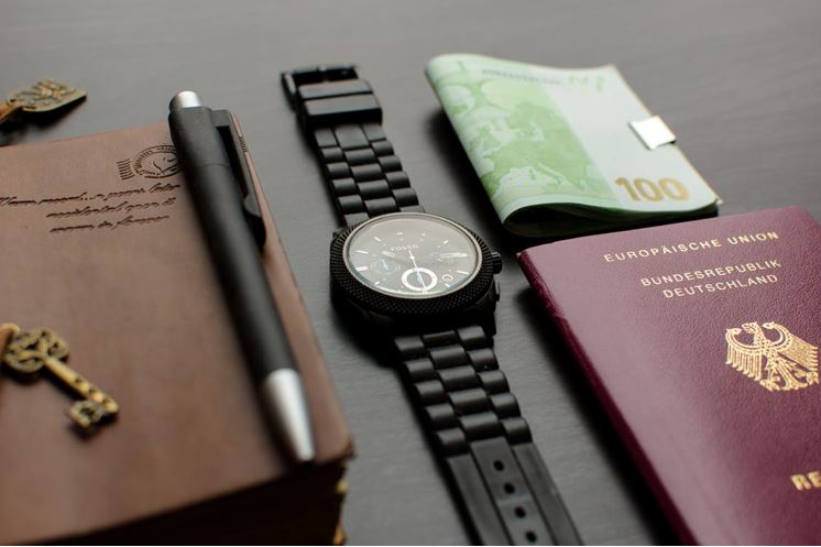 A passport, watch, and money on a table